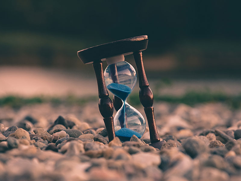 An hourglass on gravel. The sand amount is roughly equal for both ends.