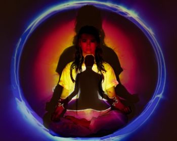 A person sits crossed legged inside a sphere of different color lights, seeming to be in a trance-like state