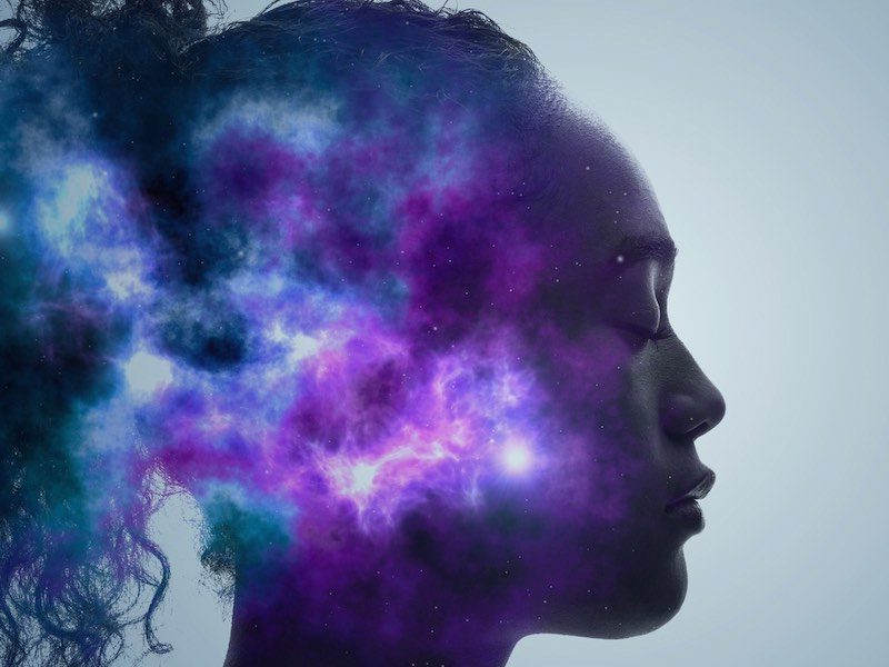 Profile of a woman with eyes closed, her head filled with cosmic nebula imagery—symbolizing inner awareness and spiritual development through meditation.